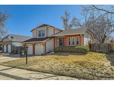 Charming two-story home features a well-manicured lawn and an attached two-car garage at 13294 W 65Th Dr, Arvada, CO 80004