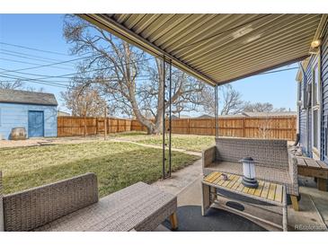 Inviting backyard with covered patio, ideal for outdoor relaxation and entertainment with a large tree in the yard at 1701 W 50Th Ave, Denver, CO 80221