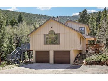 Two-story home featuring a two-car garage and elevated deck access, nestled against a mountainside at 10469 Christopher Dr, Conifer, CO 80433