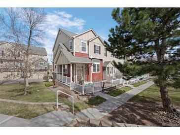 Charming tan and red townhome featuring a quaint front porch and well-maintained lawn at 1479 Nemrick Pl, Castle Rock, CO 80109