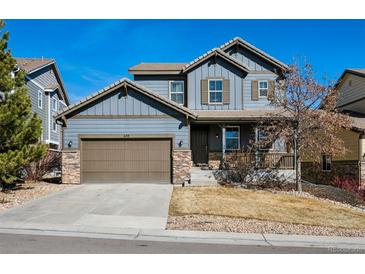 Charming two-story home with a blue facade, stone accents, a well-kept lawn, and a two-car garage at 655 Tiger Lily Way, Highlands Ranch, CO 80126