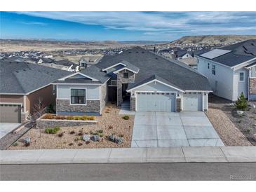 Charming exterior with three-car garage, gravel landscaping, and mountain view in the distance at 815 Alumroot St, Castle Rock, CO 80104