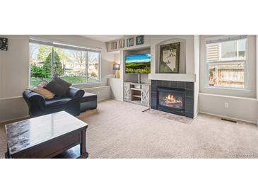 Inviting living room features a cozy fireplace, large windows, and comfortable seating, perfect for relaxation at 11373 Kearney Way, Thornton, CO 80233