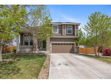 Beautiful home showcasing a well-maintained lawn, stone details, and an attached garage at 12616 Jersey W Cir, Brighton, CO 80602