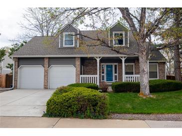 Charming two-story home with a brick facade, a well-manicured lawn, and a two-car garage at 7334 S Moore St, Littleton, CO 80127