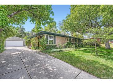 Charming single-story brick home featuring a well-manicured lawn and mature trees at 8600 W 2Nd Ave, Lakewood, CO 80226