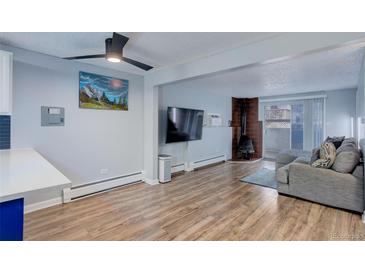Inviting living room with a fireplace, ceiling fan, wood flooring, and sliding glass doors at 1585 S Holly St # 109, Denver, CO 80222