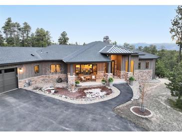 Stunning front exterior showcasing stone accents, covered porch, manicured landscaping, and an inviting circular driveway at 17548 Colonial Park Dr, Monument, CO 80132