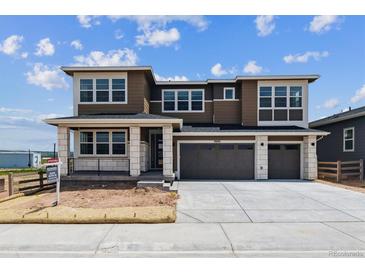 Two story home with large garage, neutral colors, white stone porch accents, and professionally landscaped front yard at 8686 Pennycress Dr, Littleton, CO 80125