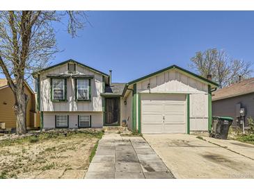 Charming home featuring a two-car garage, white siding, green trim, and a well-lit entryway with concrete walkway at 18891 E Carmel Dr, Aurora, CO 80011