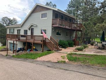 Charming two-story home boasts a spacious deck, landscaped yard, and an inviting entrance at 4724 Hopi Rd, Indian Hills, CO 80454