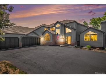 Beautiful exterior of home with three-car garage and a well-maintained asphalt driveway at sunset at 5542 Ponderosa Dr, Parker, CO 80134