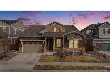 Charming home exterior featuring stone accents, covered porch, and well-maintained landscaping during twilight hours at 10114 Atlanta St, Parker, CO 80134