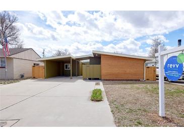 Modern home featuring wooden siding, a carport, and a well-kept concrete driveway with lush green foliage at 5350 E 66Th Way, Commerce City, CO 80022