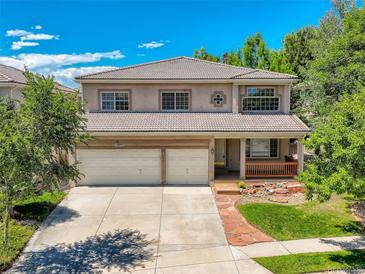 Charming two-story home featuring a well-maintained lawn, a two-car garage, and a cozy front porch at 13895 Sandtrap Cir, Broomfield, CO 80023