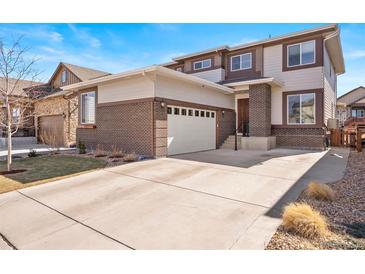 Attractive two-story home featuring a brick and neutral-toned exterior with an attached two-car garage and a well-maintained front lawn at 18926 W 93Rd Ave, Arvada, CO 80007