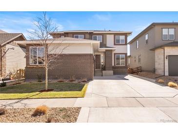 Inviting two-story home with brick accents, well-manicured lawn, and a spacious driveway at 18926 W 93Rd Ave, Arvada, CO 80007