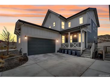 Charming two-story home with a gray garage door, inviting front porch, and a warm sunset backdrop at 631 Felicity Loop, Castle Rock, CO 80109