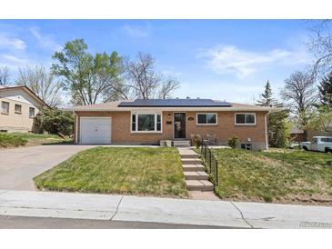 Charming brick home with solar panels, landscaped lawn, and inviting front entrance at 4102 W Eastman Ave, Denver, CO 80236