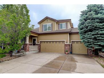 Charming two-story home featuring a three-car garage, a welcoming front porch, and mature trees at 15372 E 117Th Ave, Commerce City, CO 80022