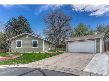 Charming single-story home with green siding, detached garage, manicured lawn and mature trees on a sunny day at 9401 Otis St, Broomfield, CO 80021