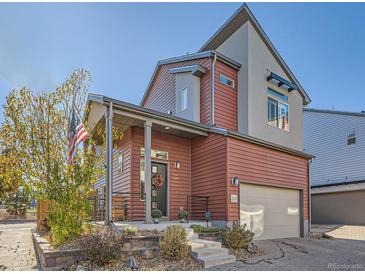 Inviting two-story home with red siding, well-kept landscaping, covered porch, and attached garage at 2514 Sweet Wind Ave, Castle Rock, CO 80109