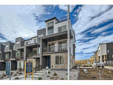 Modern three-story townhome with balcony and landscaped front yard at 16551 Peak Way, Broomfield, CO 80023