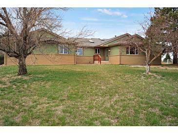 Charming ranch-style home with green siding and brick accents, set on a spacious lawn at 12337 2Nd St, Parker, CO 80134