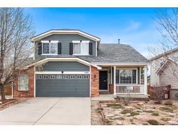 Charming two-story home featuring a landscaped front yard, a two-car garage, and a cozy front porch at 1461 Hickory Ct, Erie, CO 80516