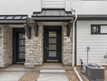 Inviting townhome entrance with stone facade, modern door, and sleek black awning at 2046 S Holly St # 1, Denver, CO 80222