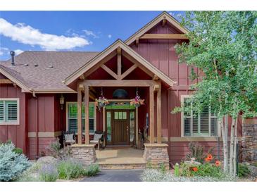 Charming home entrance featuring a covered porch, stone accents, and manicured landscaping at 31189 Manitoba Dr, Evergreen, CO 80439