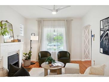 Cozy living room features a fireplace, two armchairs, modern ceiling fan, and large window with sheer curtains at 3316 N Columbine St, Denver, CO 80205