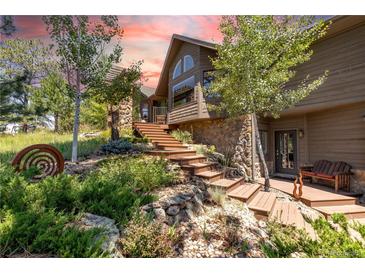 Stunning home exterior featuring stone accents, a wooden staircase, and lush landscaping under a vibrant sunset sky at 8361 Piney Creek Rd, Parker, CO 80138