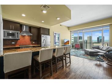 Modern kitchen with stainless steel appliances and granite countertops with seating, adjacent to open living area at 2001 Lincoln St # 2420, Denver, CO 80202