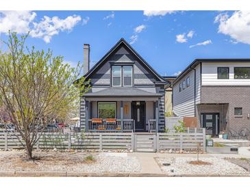 Charming gray two-story home with a fence, lush landscaping, and inviting front porch at 2135 W 40Th Ave, Denver, CO 80211