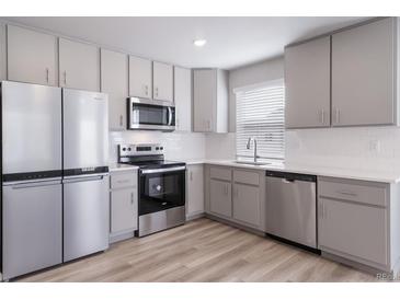 This is a modern kitchen with stainless steel appliances and gray cabinets at 46566 Avery Ln, Bennett, CO 80102