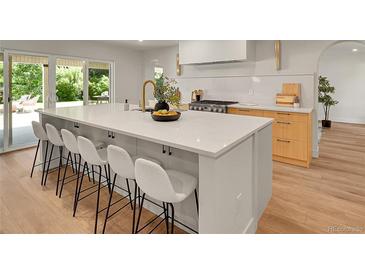 Bright kitchen boasts a large island with seating and sleek countertops, perfect for entertaining and modern living at 3736 S Hibiscus Way, Denver, CO 80237
