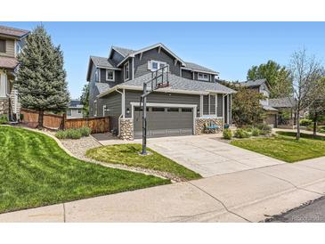 Charming home with a basketball hoop, stone accents, a well-manicured lawn, and a two-car garage at 9921 W Edenburg Pl, Littleton, CO 80127