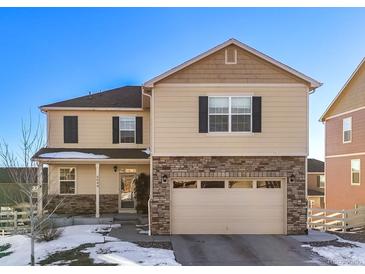 Two-story house with tan siding, stone accents, and a two-car garage at 6044 Point Rider Cir, Castle Rock, CO 80104