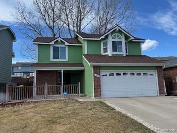 Charming two-story green home boasts a two-car garage, landscaped front yard, and welcoming curb appeal at 12025 Monaco Dr, Brighton, CO 80602