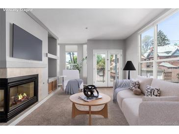 Bright living room features a fireplace, plush carpet, and a balcony with views at 1521 Vine St # 108, Denver, CO 80206