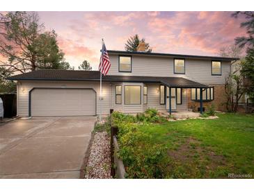 Charming two-story home featuring an attached garage and a well-maintained front yard with an American flag at 930 S Dayton St, Denver, CO 80247