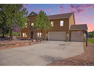 Charming two-story home with a three-car garage, basketball hoop, stone accents, and professionally landscaped front yard at 1822 Painter Dr, Monument, CO 80132