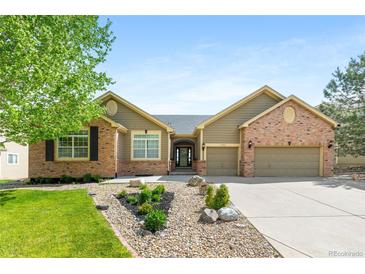 Beautiful, well-maintained home showcasing a manicured front yard, brick accents, and attached two car garage at 7120 Red Mesa Dr, Littleton, CO 80125