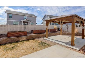 A backyard with a gazebo, garden boxes, a white fence, and well-manicured lawn and landscaping at 5322 Sandy Ridge Ave, Firestone, CO 80504