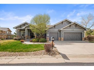 Charming gray home featuring a manicured lawn, stone accents, and a two-car garage at 7003 S Irvington Ct, Aurora, CO 80016