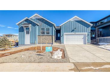 Attractive blue home with modern architectural design elements, an attached garage, and landscaped front yard at 8606 Hotchkiss St, Littleton, CO 80125