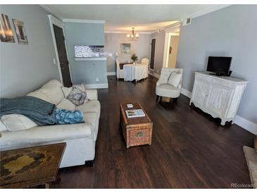 Cozy living room featuring hardwood floors, comfortable seating, and an open view into the dining area at 1863 S Pitkin Cir # B, Aurora, CO 80017
