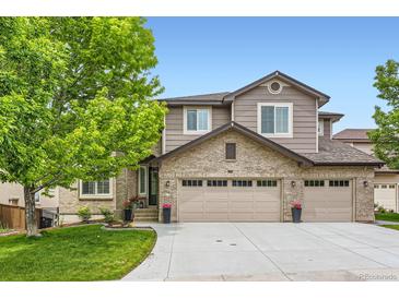 Charming home featuring a brick and siding exterior, three-car garage, manicured lawn, and mature tree at 989 Graland Pl, Highlands Ranch, CO 80126