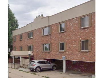 Three-story brick apartment building with covered parking and tan trim at 155 S Pennsylvania St # 209, Denver, CO 80209